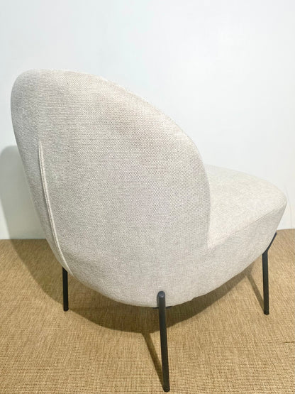 Fauteuil enveloppant en tissu beige sur pieds en métal noir