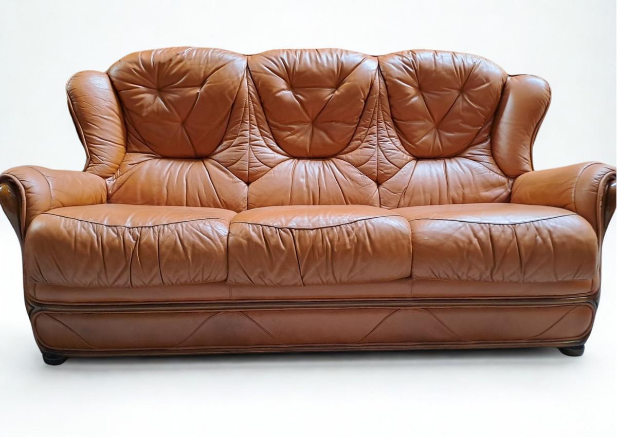 Canapé trois places en cuir cognac capitonné et son pouf