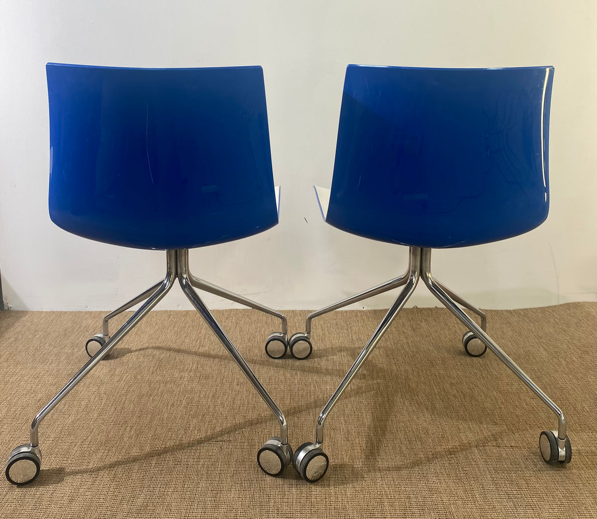 Paire de chaises coque en plastique blanc à roulettes