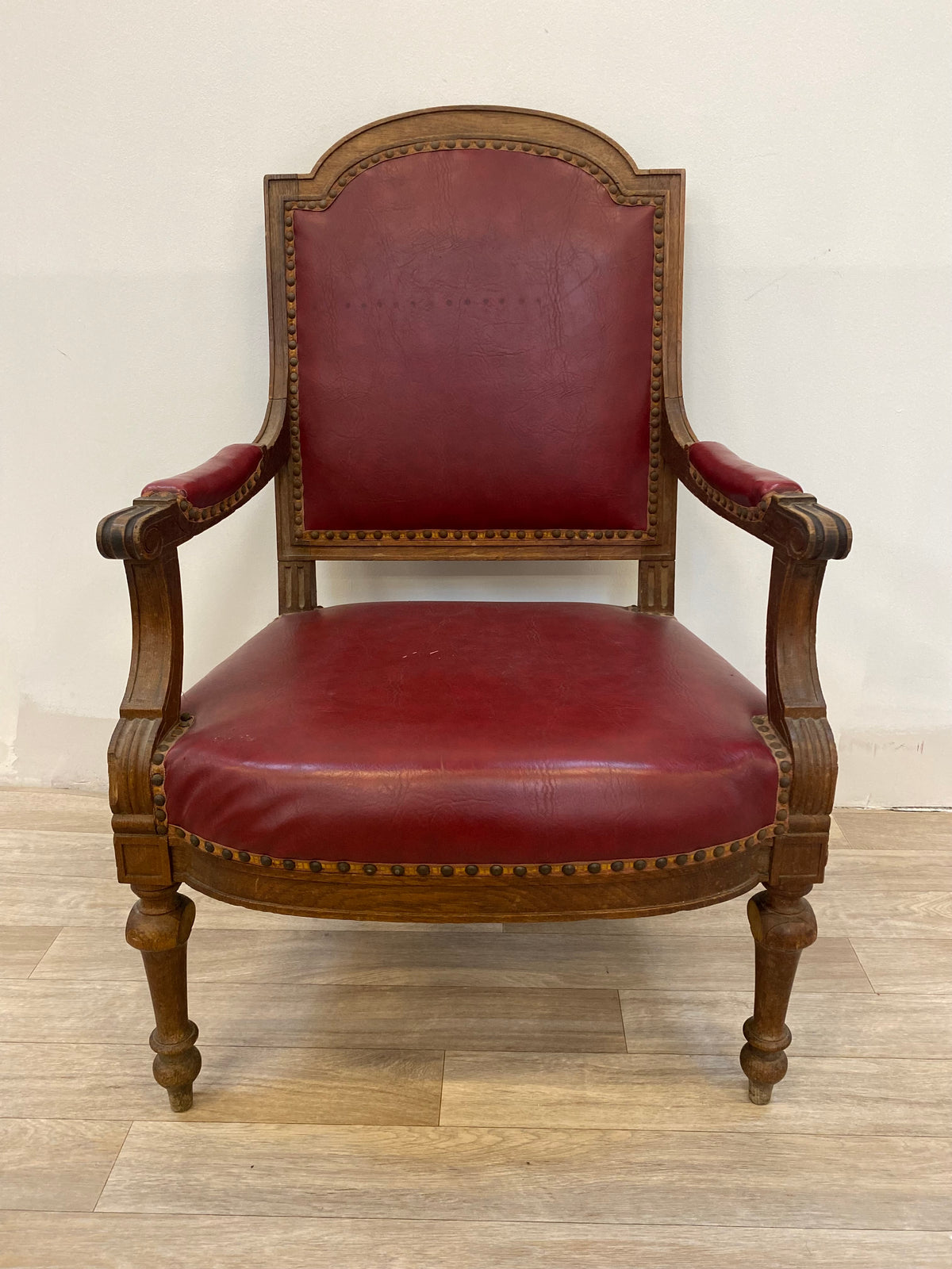 Fauteuil en bois sculpté et cuir bordeaux clouté