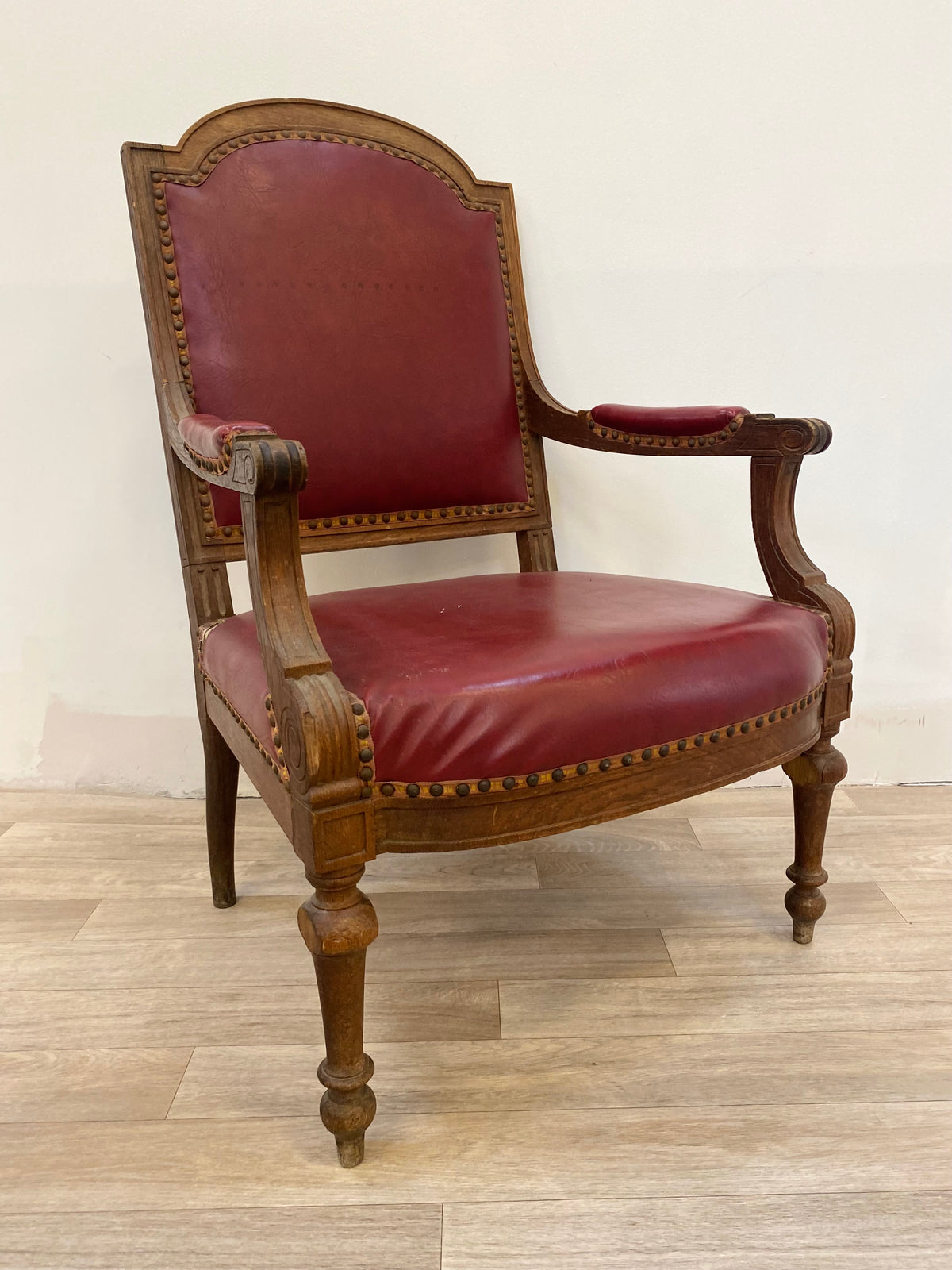 Fauteuil en bois sculpté et cuir bordeaux clouté