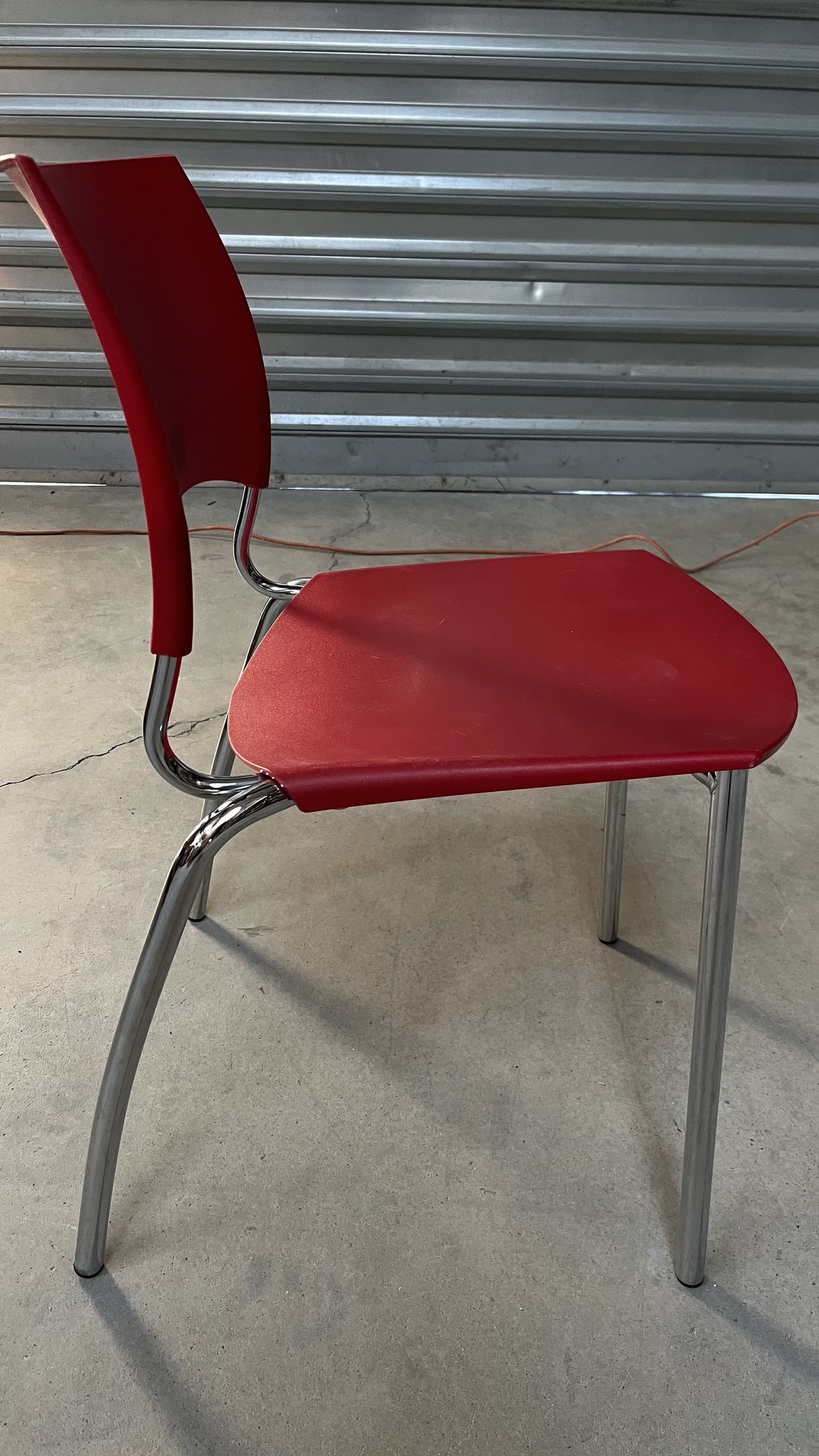 Chaise en plastique rouge sur pieds en métal gris
