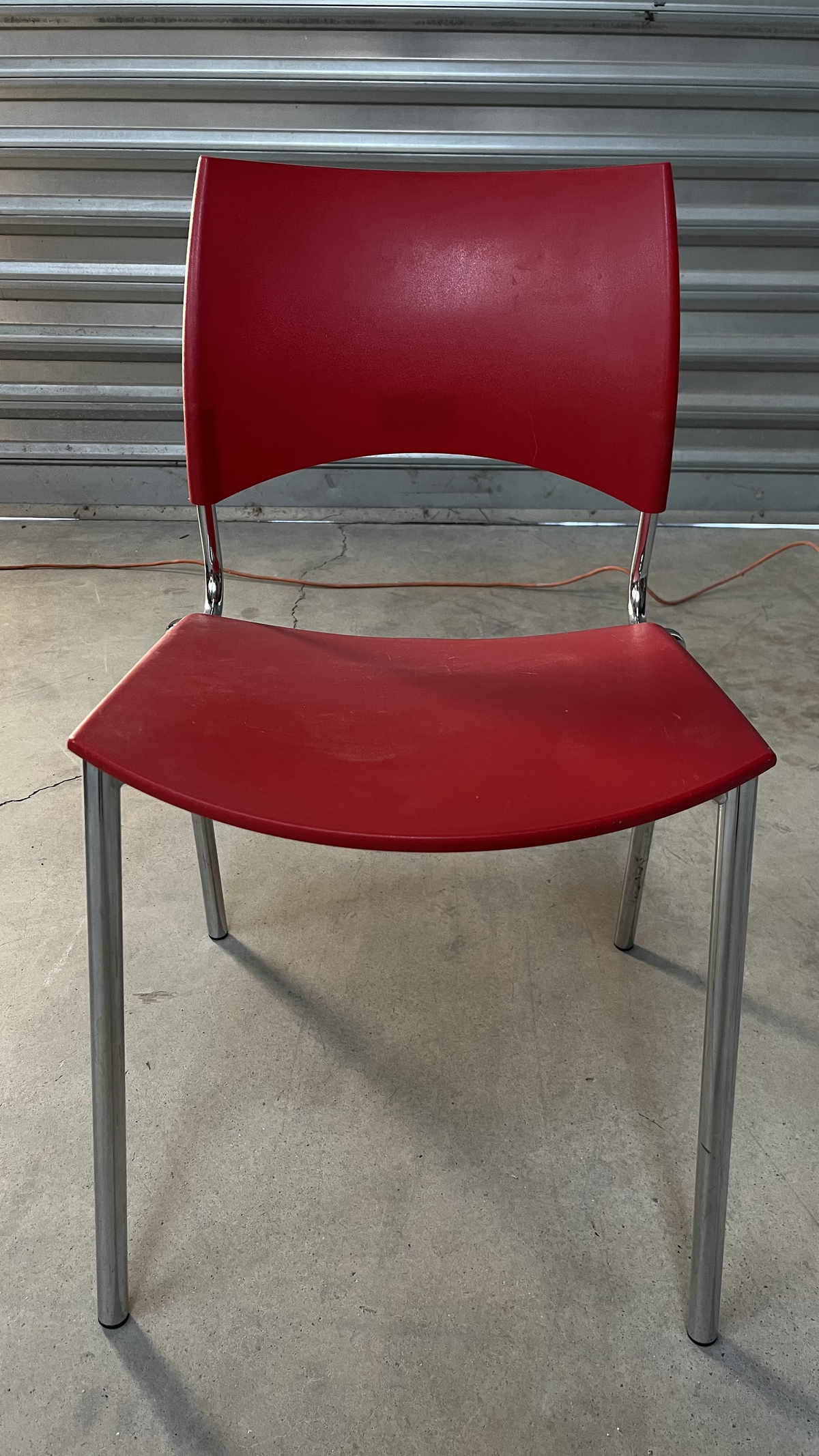 Chaise en plastique rouge sur pieds en métal gris
